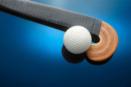 Golf ball and hockey stick on a blue background. Close-upの写真素材
