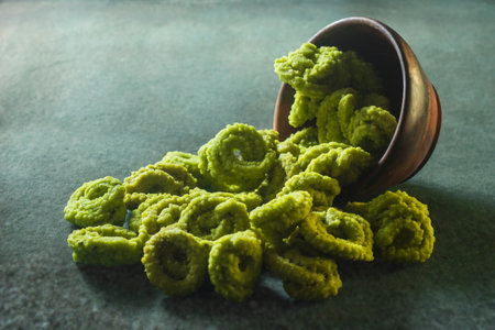 Green cornflakes in a wooden bowl on a green background.