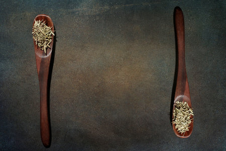 Spices in wooden spoons on a dark background, top viewの写真素材