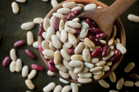 Dry beans in a wooden spoon on a rustic background.