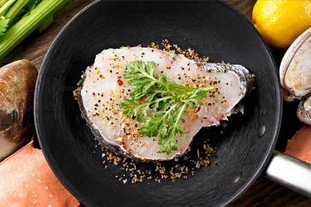 Fresh raw fish fillet with parsley and lemon on black frying pan