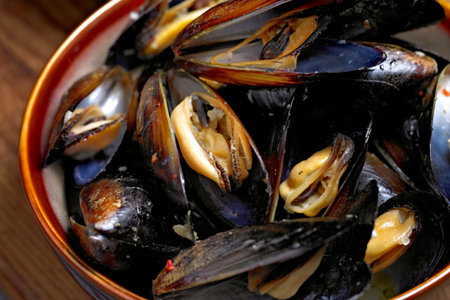 Mussels in a bowl on a wooden table, close-up