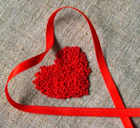 scarlet ribbon and beads heart on the canvasの写真素材