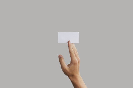 Businessman's hand holding blank paper business card, closeup isolated on grey background.の写真素材
