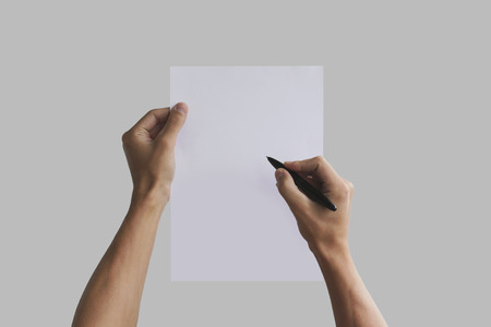 Hand holding blank agreement mockup and signing it. Arm hold clear document template mock up. Contract surface design. Simple pure legal paper print display. Reading contract statement.の写真素材