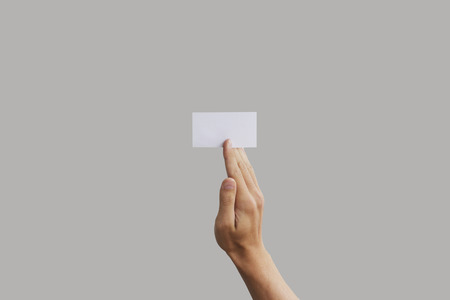 Businessman's hand holding blank paper business card, closeup isolated on grey background.の写真素材