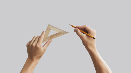 Hands hold the pencil with triangular wooden ruler. Isolated grey.の写真素材