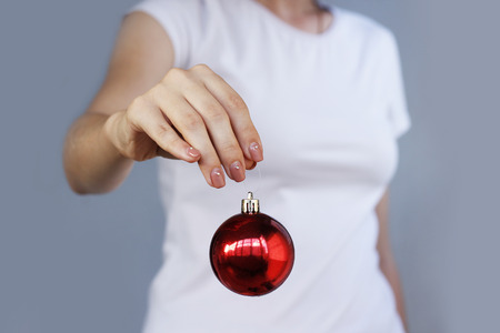 Girl in white t-shirt holding Christmas toy red ball.の写真素材