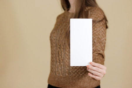 Girl showing blank white flyer brochure booklet. Leaflet presentation. Pamphlet hold hands. Woman show clear offset paper. Sheet template. Booklet design sheet display read first personの写真素材