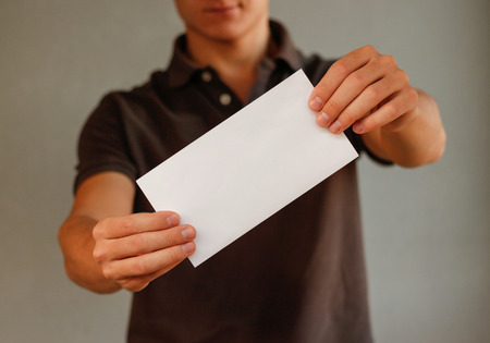 Man showing aslant blank white flyer brochure booklet. Leaflet presentation. Pamphlet hold hands. Man show clear offset paper. Sheet template. Booklet design sheet display read first personの写真素材