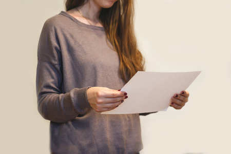 Girl reading A4 blank white flyer brochure booklet. Leaflet presentation. Pamphlet hold hands. Woman show clear offset paper. Sheet template.の写真素材