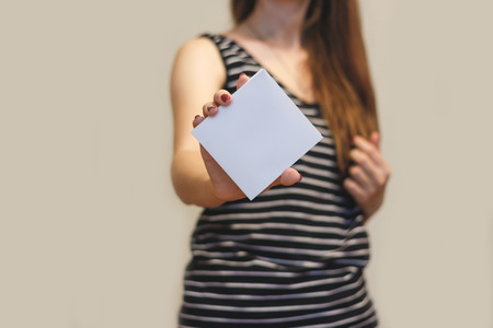 Girl showing blank white square flyer brochure booklet. Leaflet presentation. Pamphlet hold hands. Woman show clear offset paper. Sheet template. Booklet design sheet display read first personの写真素材