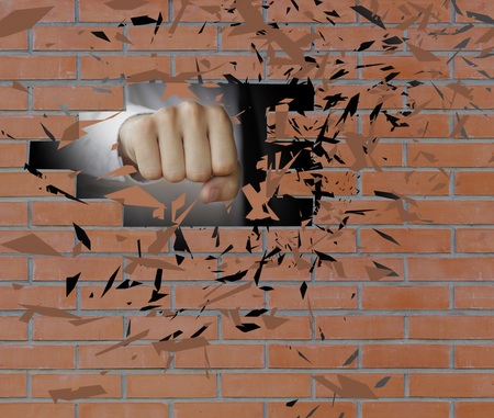 Fist smashes a brick wall to smithereens. Man hand breaking wall.の写真素材