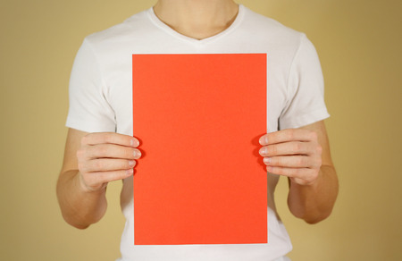 Man holding red A4 paper vertically. Leaflet presentation. Pamphlet hold hands. Man show clear offset paper. Sheet template. Booklet design sheet display read first personの写真素材