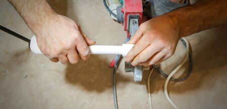 Plumber weld two pieces of white polypropylene pipes.