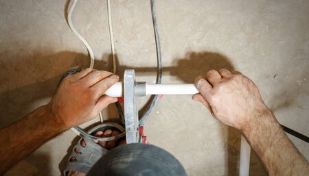 Plumber weld two pieces of white polypropylene pipes. View first person.