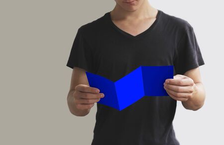 Man reading blank blue flyer brochure booklet. Leaflet presentation. Pamphlet hold hands. Man show clear offset paper. Sheet template.の写真素材