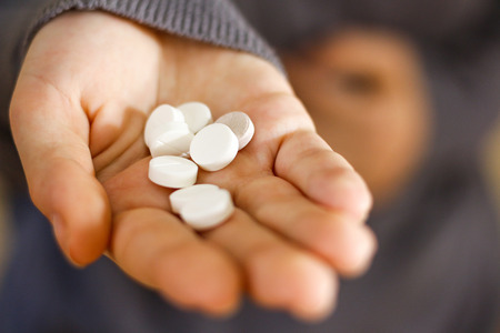 Treatment tablets. Close-up of a white pill in woman's fingers.の写真素材