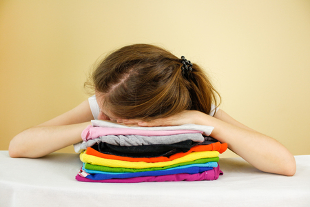 Girl lying on a stack of ironed colored linen. Pile of clothes. Ironing concept.の写真素材