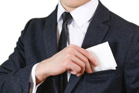 Close up hand puts a white handkerchief in the pocket of his black jacket.の写真素材