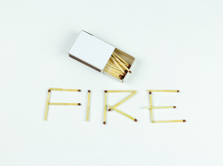 Closeup outdoor white boxes of matches. Scattered matches. Matches laid out the word Fire. Isolated on white background.の写真素材