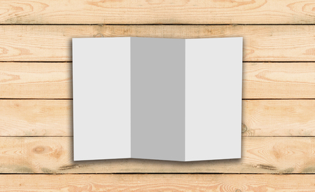 Blank Trifold white template paper on wood background with soft shadows. Ready for your designの写真素材