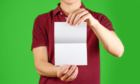 Man showing blank white flyer brochure booklet. Leaflet presentation. Pamphlet hold hands. Man show clear offset paper. Sheet template. Booklet design sheet display read first person. On chromakeyの写真素材