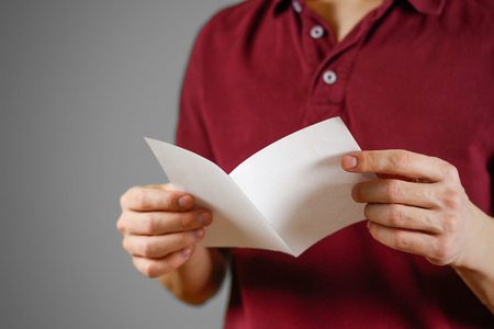 Man reading blank white flyer brochure. Read detailed booklet. Leaflet presentation. Pamphlet hold hands. Man show clear offset paper. Sheet template. Booklet design sheet display read first personの写真素材