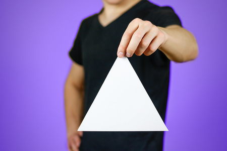 Man showing blank white triangular flyer brochure booklet. Leaflet presentation. Pamphlet hold hands. Man show clear offset paper. Sheet template. Booklet design sheet display read first person.の写真素材