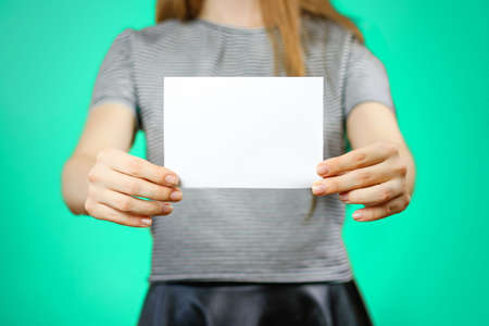 Woman showing blank white flyer paper. Leaflet presentation. Pamphlet hold hands. Girl show clear offset paper. Sheet template. Booklet design sheet display read first person.の写真素材
