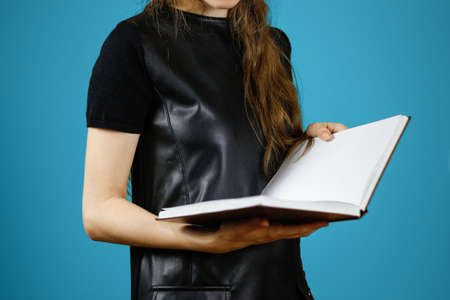 Closeup of girl in black dress holding blank open white book on isolated background. Education concept. Mock upの写真素材