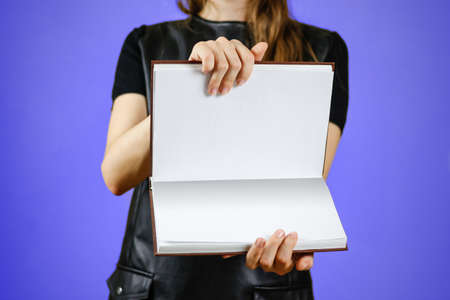 Closeup of girl in black dress holding blank open white book on isolated background. Education concept. Mock upの写真素材