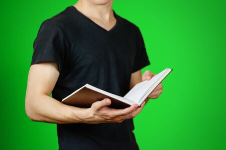 Closeup of guy in black t-shirt holding blank open white book on isolated background. Education concept. Mock up.の写真素材