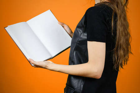 Closeup of girl in black dress holding blank open white book on isolated background. Education concept. Mock upの写真素材