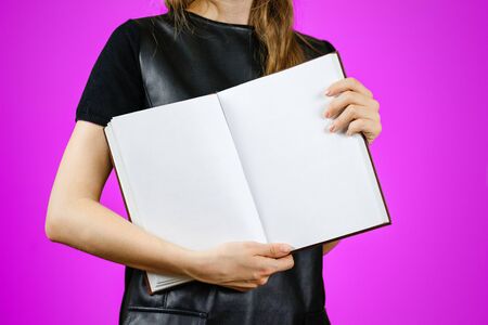 Closeup of girl in black dress holding blank open white book on isolated background. Education concept. Mock upの写真素材