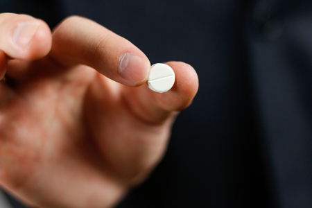 Businessman holds one round tablet with two fingers.の写真素材