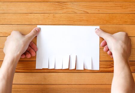 Hand attached metal buttons paper ad. Empty paper ad loose leaves on a wooden wall. Attached metal buttons. Blank advertisement with cut slips.の写真素材