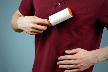 A man cleans the t-shirt sticky roller. Closeup. Isolated.の写真素材