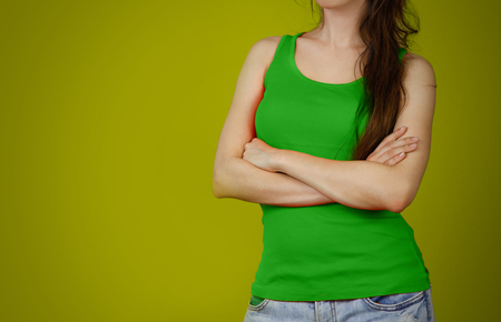 A girl in a green plain t-shirt. Empty tank top. Closeup. Isolated on yellow background.の写真素材