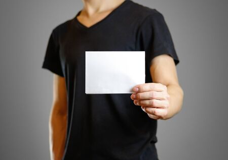 Man in a black shirt holding a white sheet of paper. Empty flyer. Isolated.の写真素材
