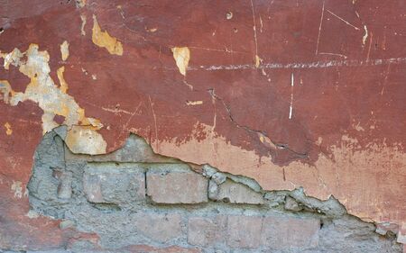 The texture of the old peeling concrete walls with bricks. One can see the bricks. The fallen wall. Closeup.の写真素材