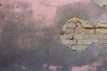 The texture of the old peeling concrete walls with bricks. One can see the bricks. The fallen wall....