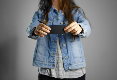 The girl in the blue denim shirt holds the white empty piece of paper. Ready for your design. Closeup. Isolated.の写真素材