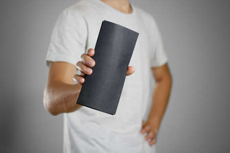 A man in a gray t-shirt holding blank clear black of the sheet. Closeup. Isolated.の写真素材