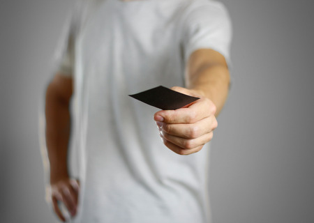 A man in a gray t-shirt holding blank clear black of the sheet. Closeup. Isolated.の写真素材