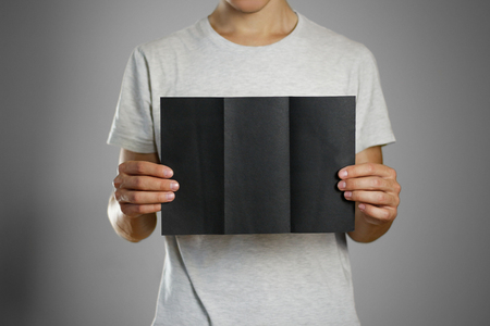A man in a gray t-shirt holding blank clear black of the sheet. Closeup. Isolated.の写真素材