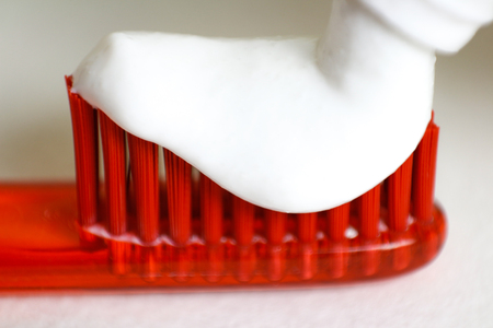 White toothpaste on an orange toothbrush. Macro. Closeup. Isolated on a white background.の写真素材