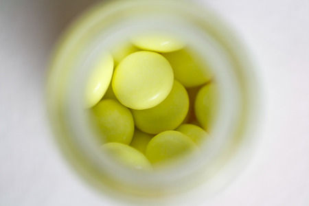 Jar of yellow tablets the top view. Macro. Closeup. Isolated on a white background.の写真素材