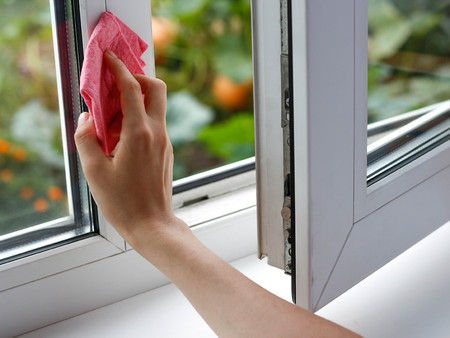 Female hand wiping the glass. Washes white plastic window. Closeup.