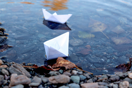 Paper boat in the river. Paper boat on the shore in the water. Closeup.の写真素材